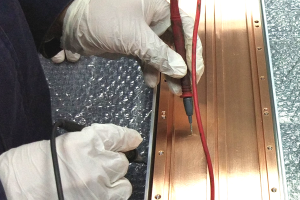电笔在铜板上测量，体现上海骏材在磁控溅射组件领域的工程技术能力